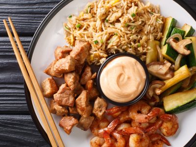 Full hibachi dish with rice, shrimp, steak and vegetables served with sauce closeup in a plate. Horizontal top view